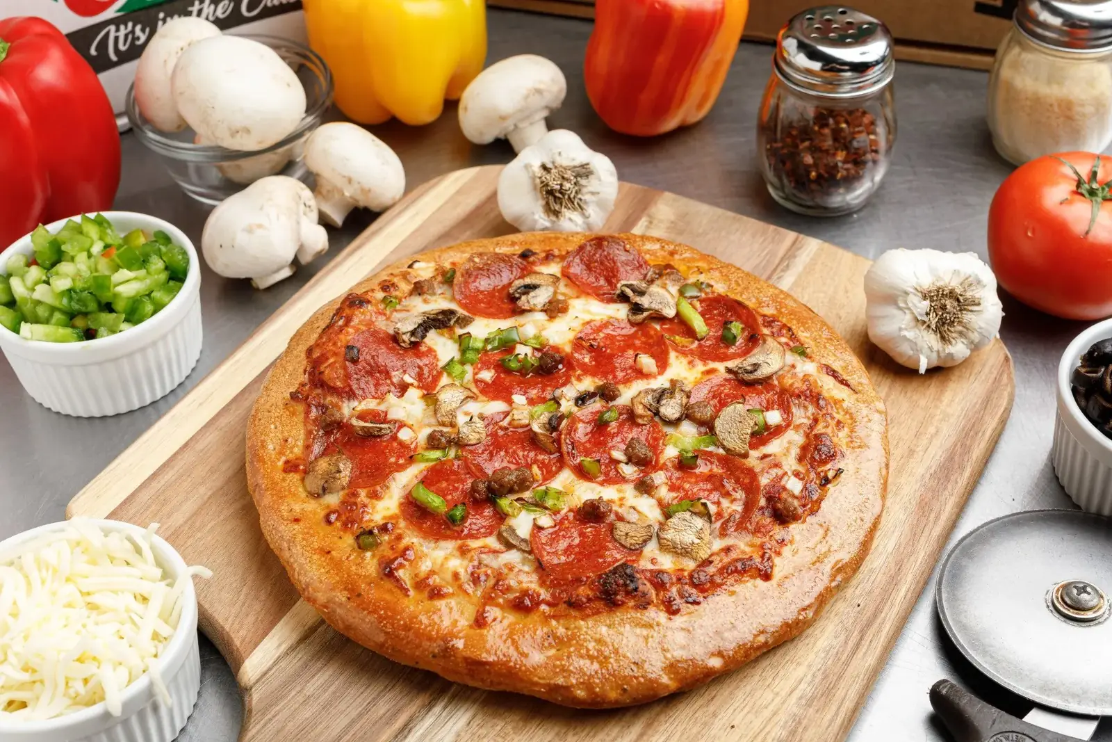 The Guy's Favorite pizza beside fresh peppers, mushrooms and garlic